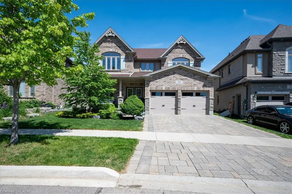 Multi-gabled brick exterior featuring a covered front porch, two-car garage, and stone-patterned paved driveway
