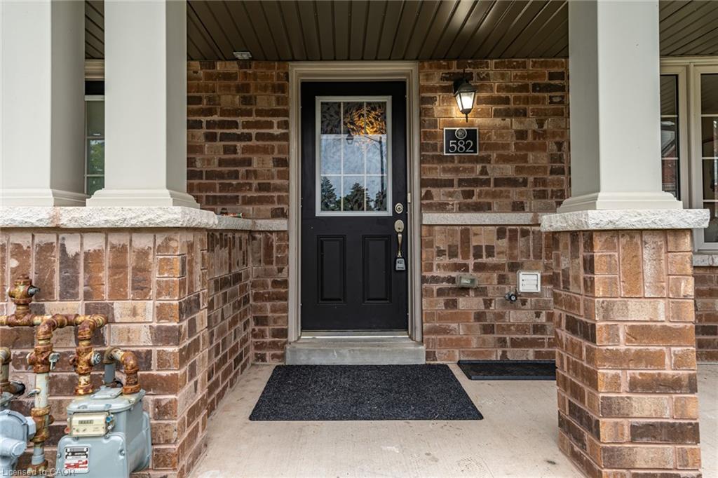 Brick facade with stone accents, black front door with decorative glass, and a covered porch