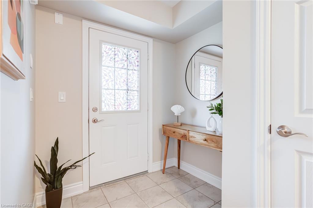 Entry with decorative glass panel door, light-toned tile flooring, and a console table with built-in drawers