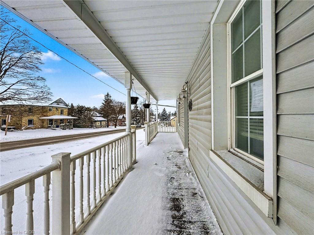 Covered front porch featuring white spindle railings, light gray siding, and an overhead lighting fixture