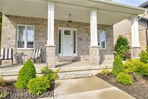 Stone facade with a covered front porch, white columns, and a white entry door with glass inserts