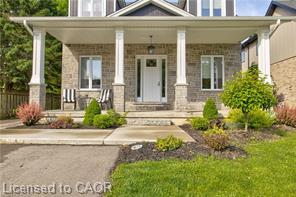 Stone facade with a covered porch, featuring white columns and a front entry door with side lites