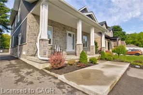 Stone veneer facade with prominent white columns, covered front porch, and landscaped garden beds