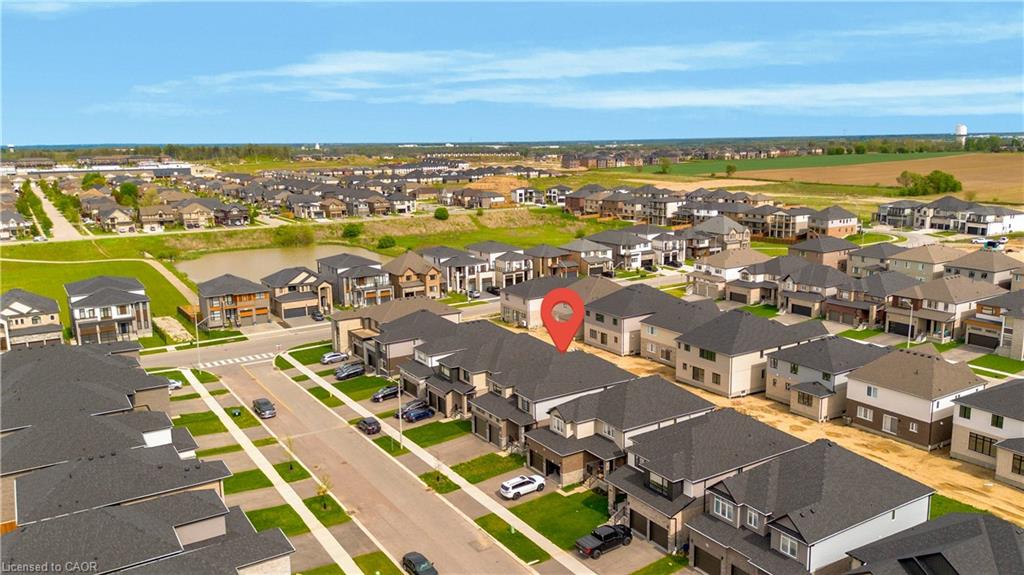 Aerial overview of a residential development featuring uniform architecture, dark shingle roofing, paved streets, and landscaped green spaces