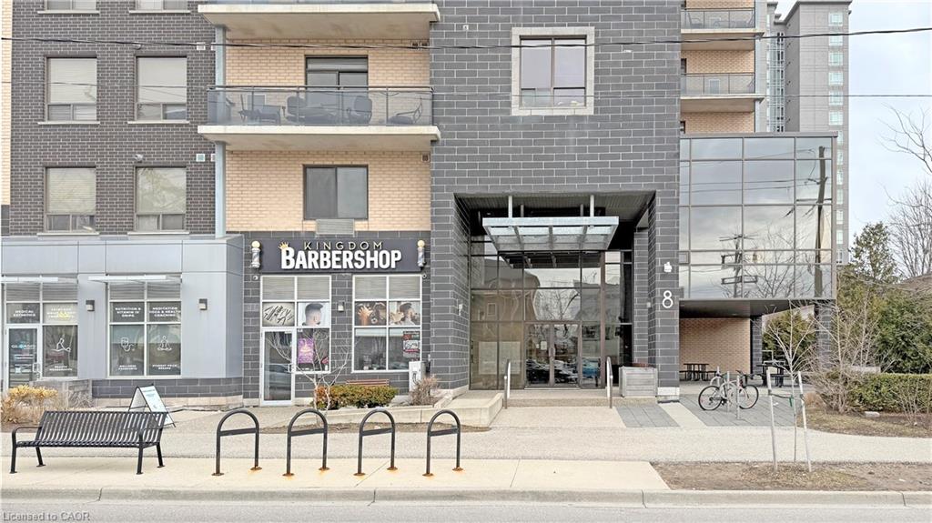 Modern multi-story building featuring a prominent glass entrance canopy and a contemporary brick facade