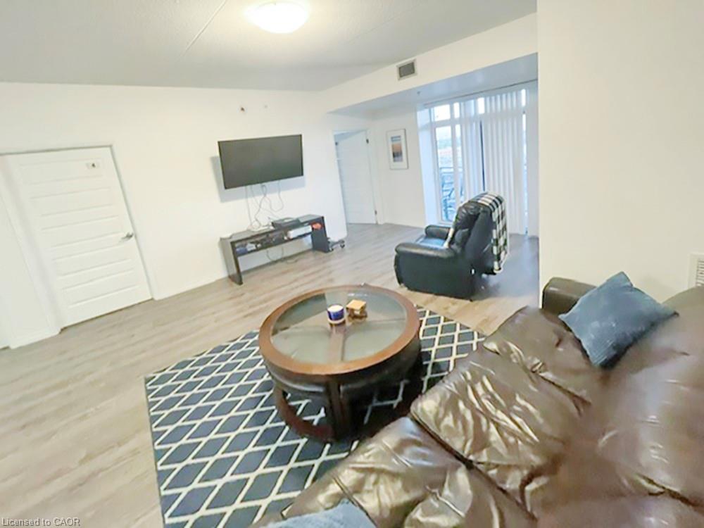 Living area featuring light wood-finish flooring, white walls, and a ceiling light fixture