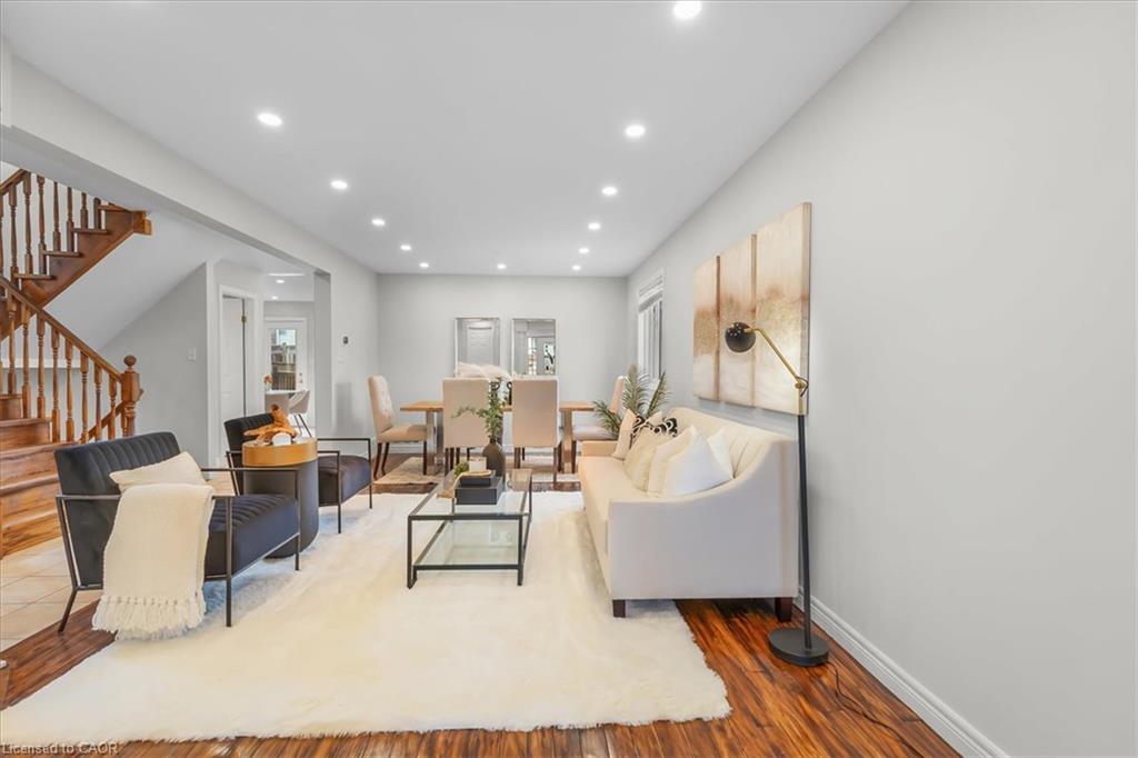 Wood-finish flooring throughout, recessed ceiling lighting, a built-in wooden staircase, and a dining area with a window