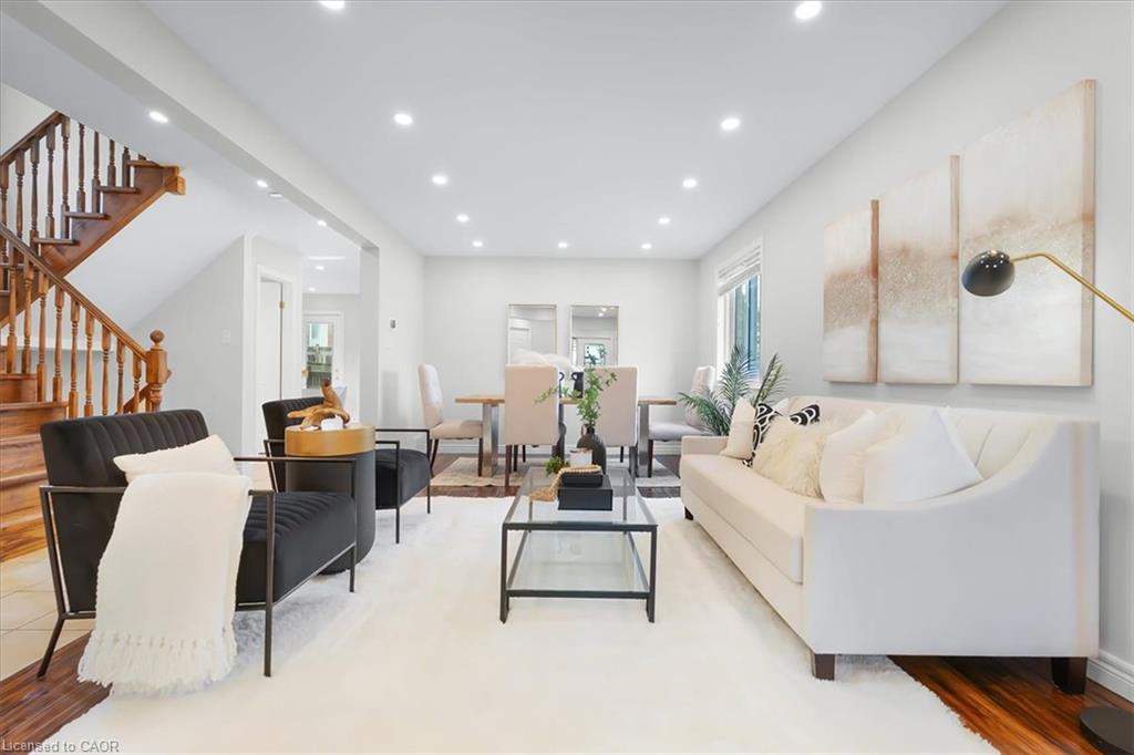 Recessed lighting illuminates the living space with wood-finish flooring