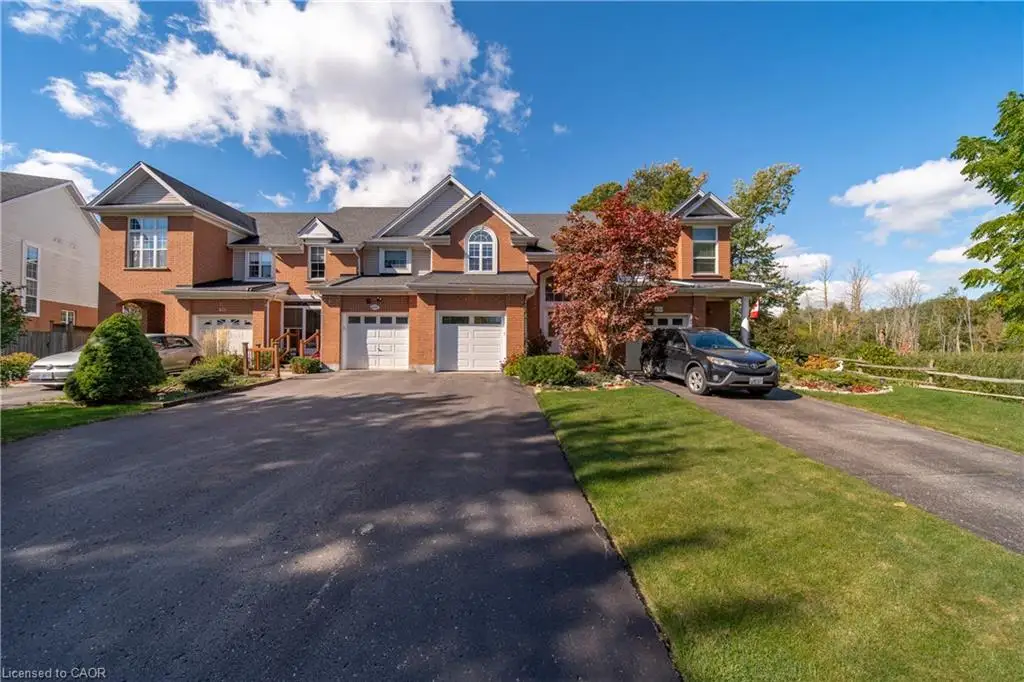 Brick exterior with multiple dormers, attached garages, and paved driveways