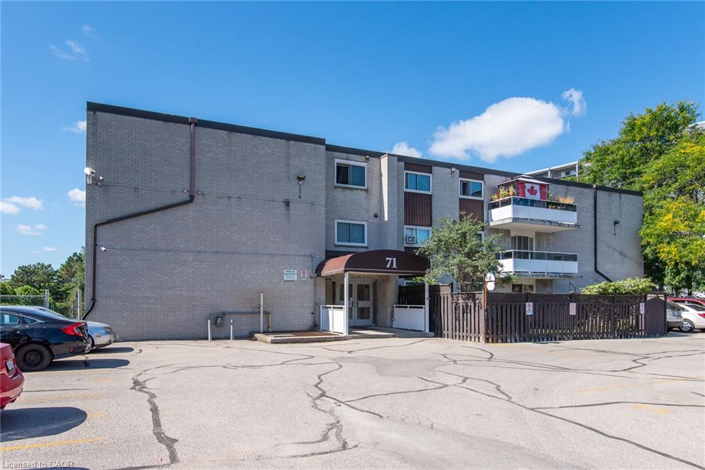 Exterior featuring a multi-story building, an asphalt parking area, and a fenced perimeter
