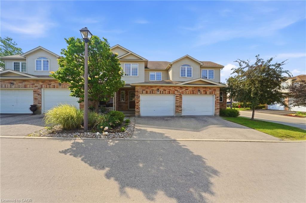 Brick Colonial-style residence featuring a two-car attached garage, manicured front landscape with ornamental lighting and mature plantings, and a circular driveway approach