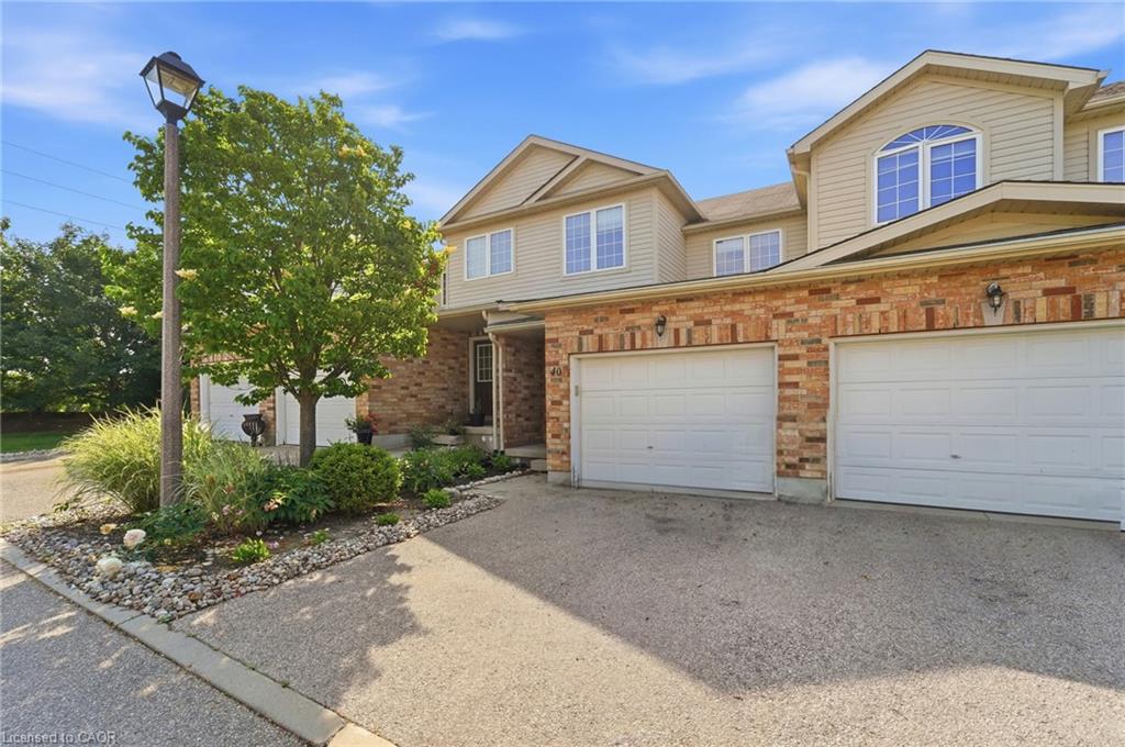 Brick and siding exterior with arched window detail, multiple garage doors, and a paved driveway