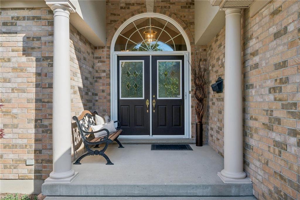 Brick facade entrance with dual columns, arched transom window, and double entry doors with decorative glass