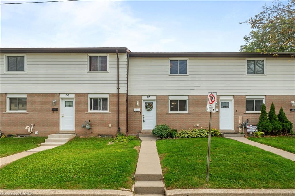Brick and siding exterior with individual entryways, mature landscaping, and concrete walkways