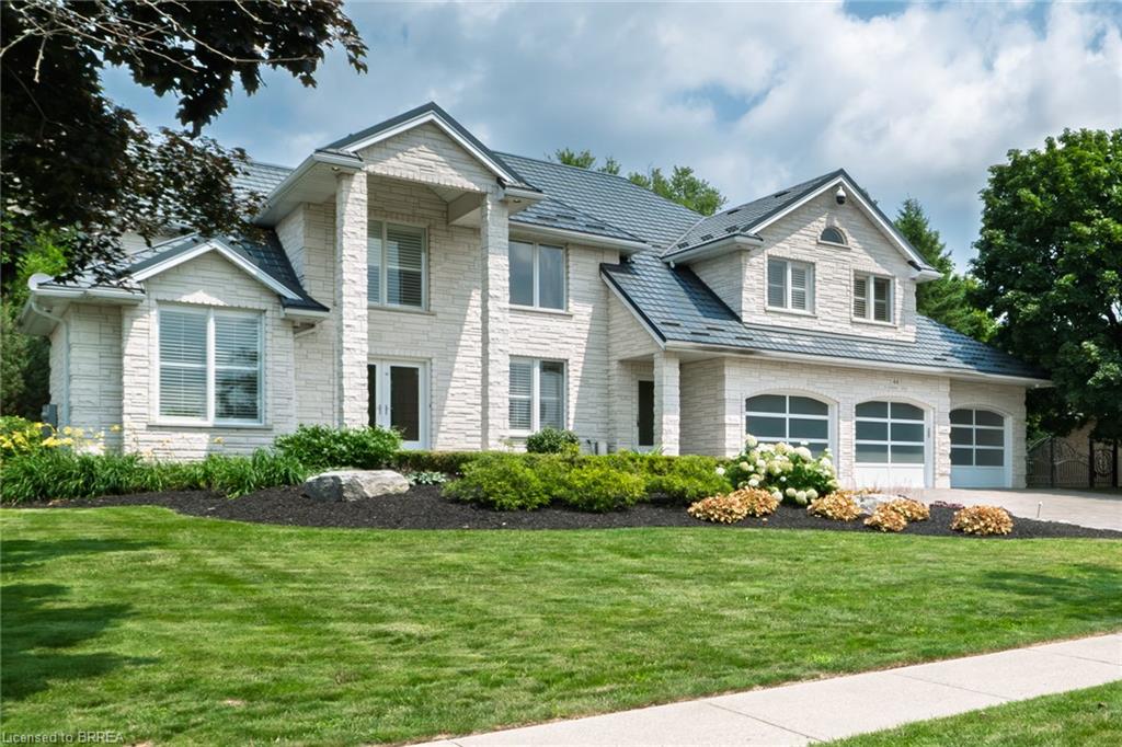 Two-story residence featuring light-colored stone exterior and a dark-colored shingled roof