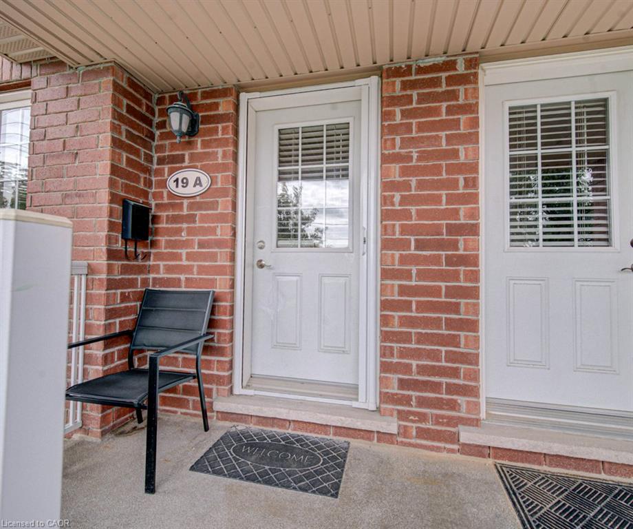 Brick exterior with a covered entryway, white entry door with integrated blinds, and an exterior wall light