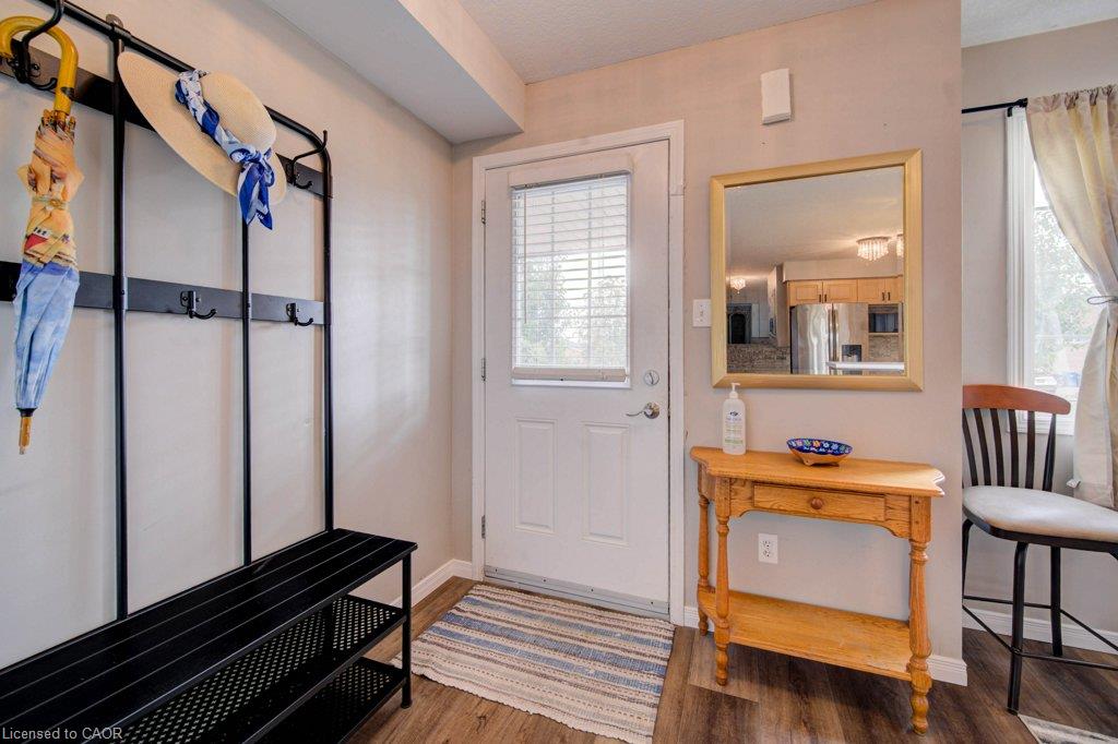 Wood-finish flooring throughout, bright white entryway door with integrated blinds, and a light-toned wood console table