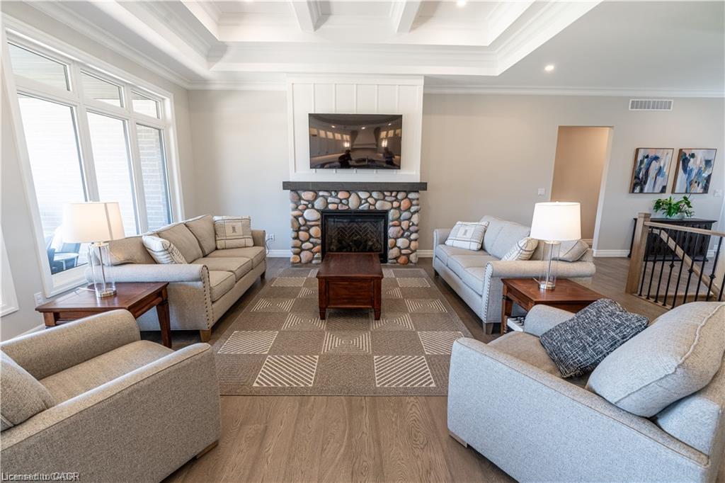 Spacious living area featuring a stone-faced fireplace with a dark wood mantel, coffered ceiling, and expansive windows