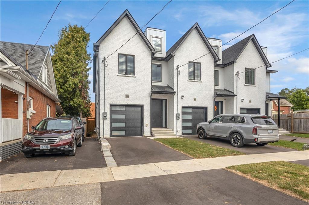 Modern architectural design featuring prominent gabled roofs, white stucco exterior, black-framed windows, and integrated garage doors with horizontal glass panels