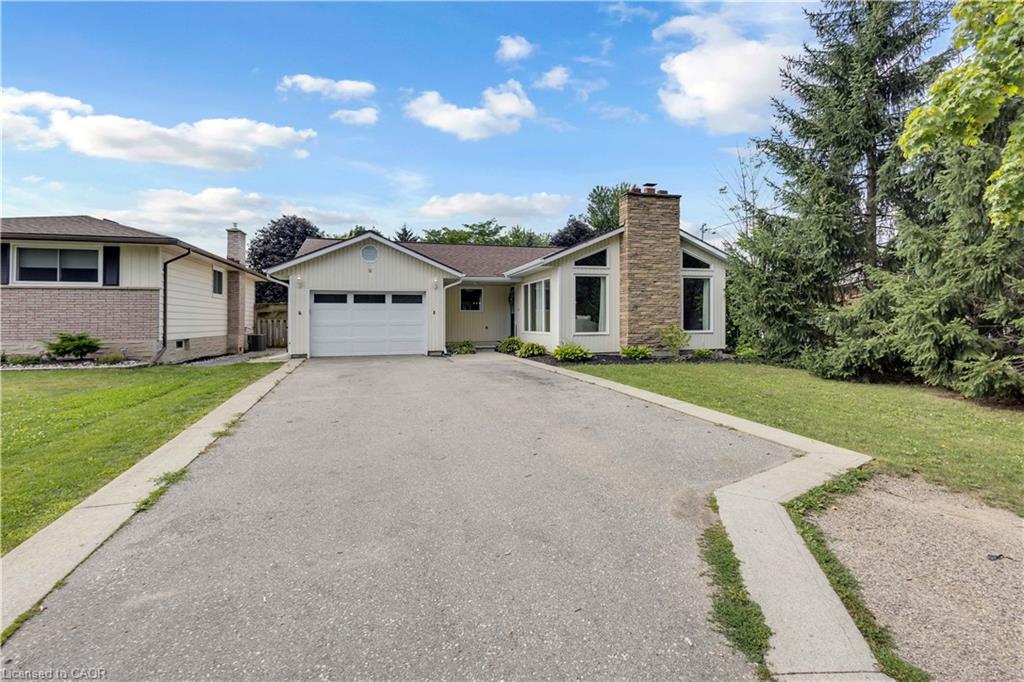 Single-story residence featuring a prominent stone-clad chimney, an attached garage, and a wide paved driveway