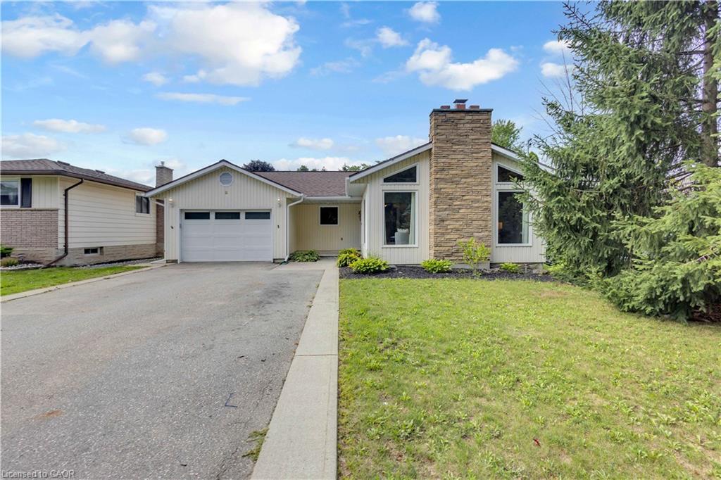 Ranch-style exterior with a stone-clad chimney, large triangular windows, an attached two-car garage, and an asphalt driveway