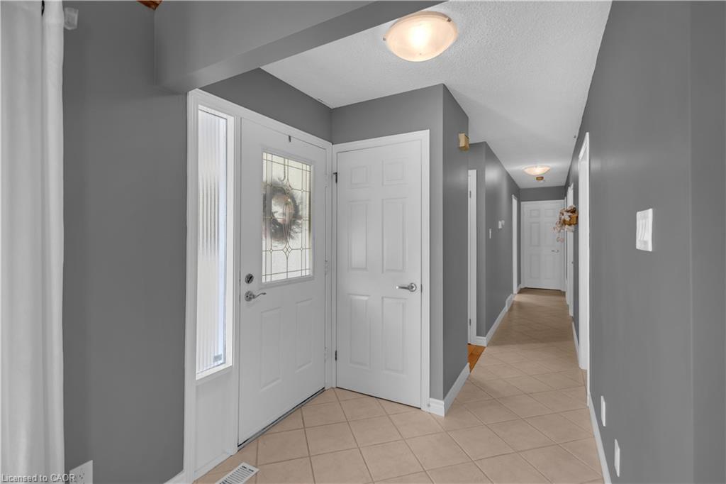 Foyer with ceramic tile flooring, white interior doors, and overhead lighting
