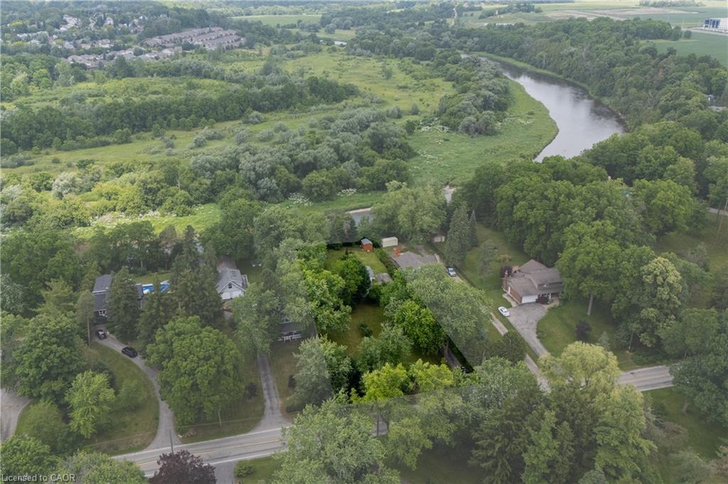 Aerial landscape featuring a winding river, dense tree lines, a residential area, and open green spaces