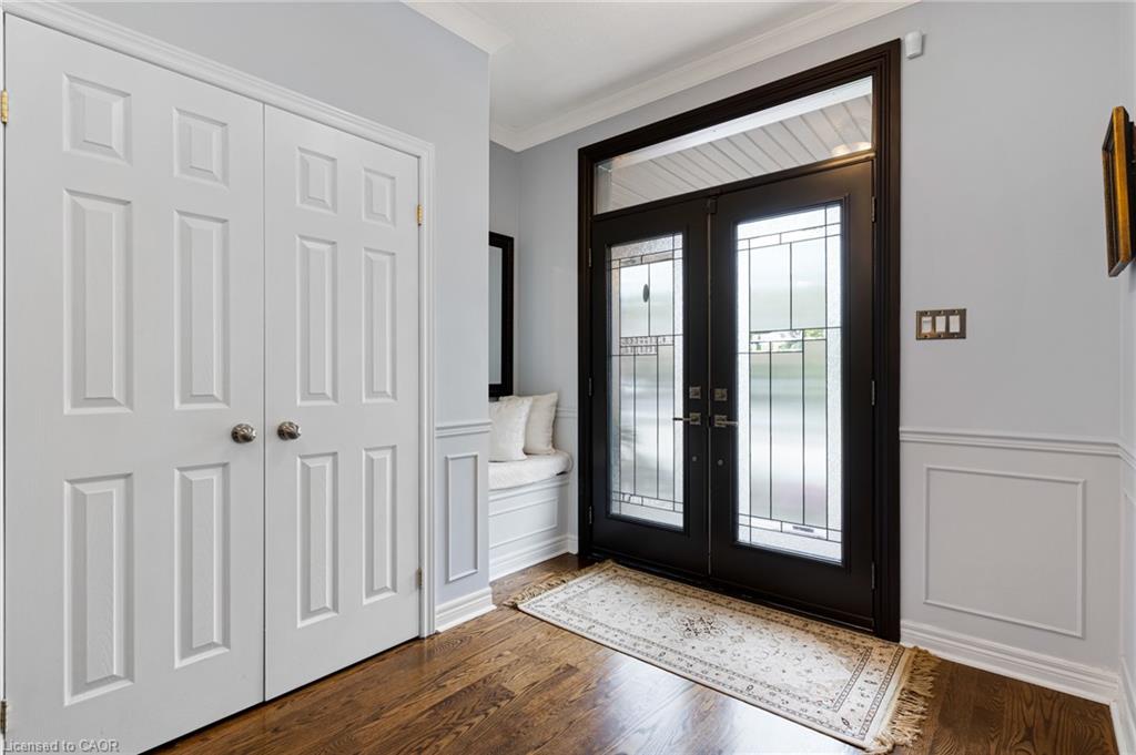 Wood-finish flooring, wainscoting, built-in bench seating, paneled bifold doors, and a double-door entry with decorative glass