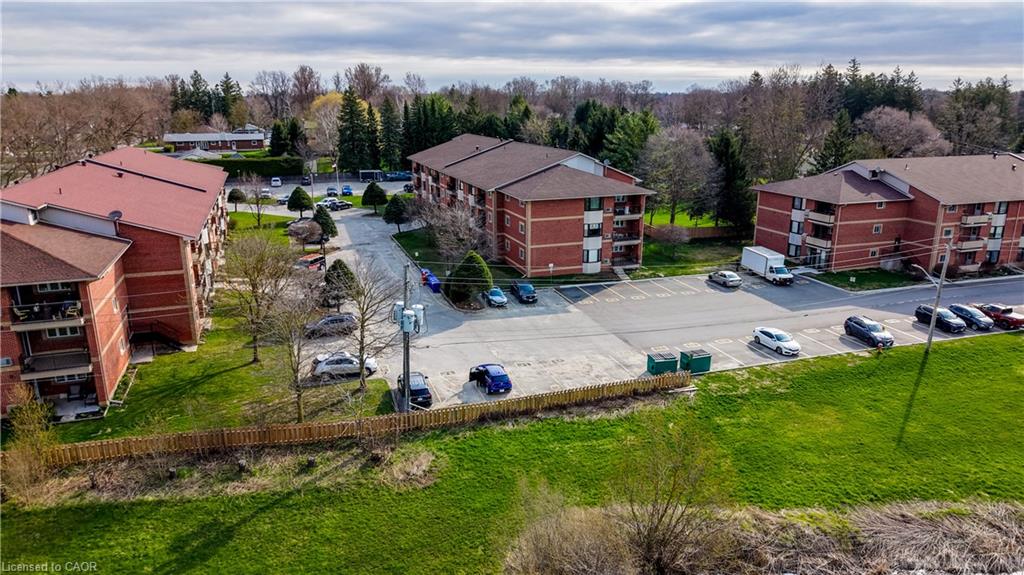 Three brick-clad apartment buildings, surface parking, and a surrounding green space with mature trees
