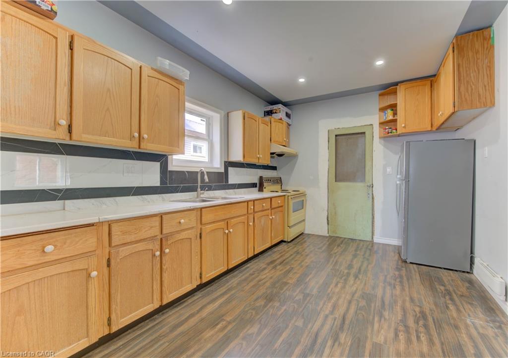 Kitchen featuring freestanding refrigerator, light countertops, white electric range oven, dark wood-type flooring, and backsplash