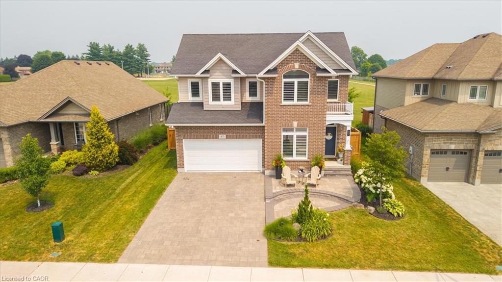 Brick and siding exterior featuring a two-car garage, arched window, and a paver stone driveway