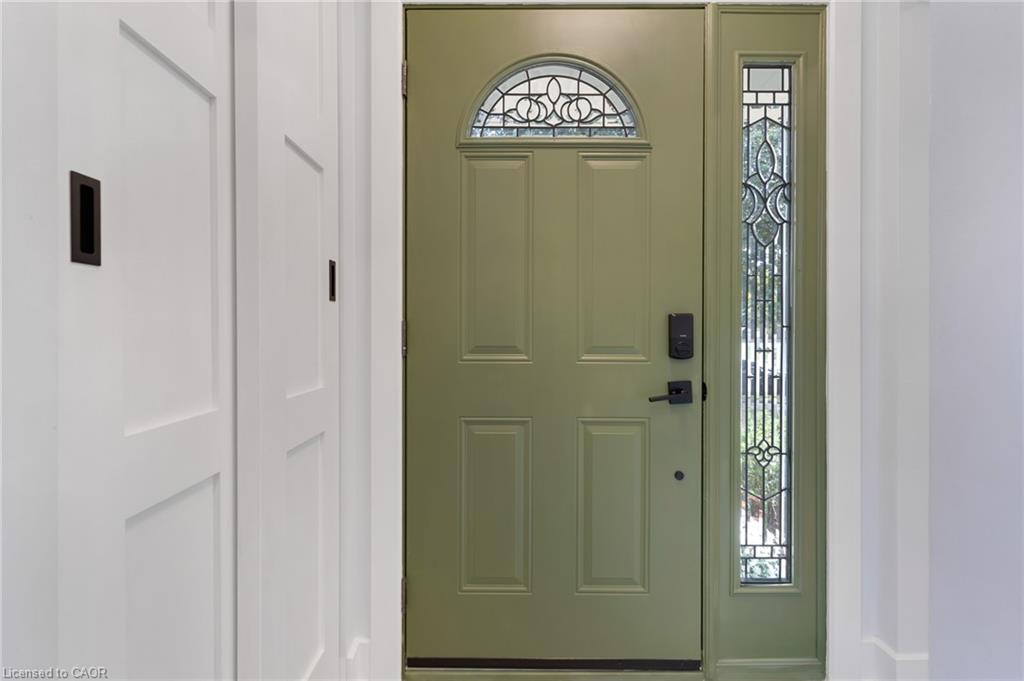 Sage green entry door with arched transom window, leaded glass sidelight, bi-fold panel doors, and tile flooring