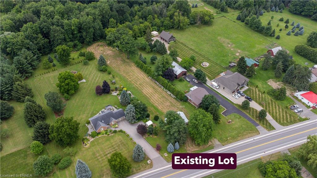 Expansive lot featuring a main residence with a dark shingle roof, extensive green lawns, mature trees, and a paved driveway