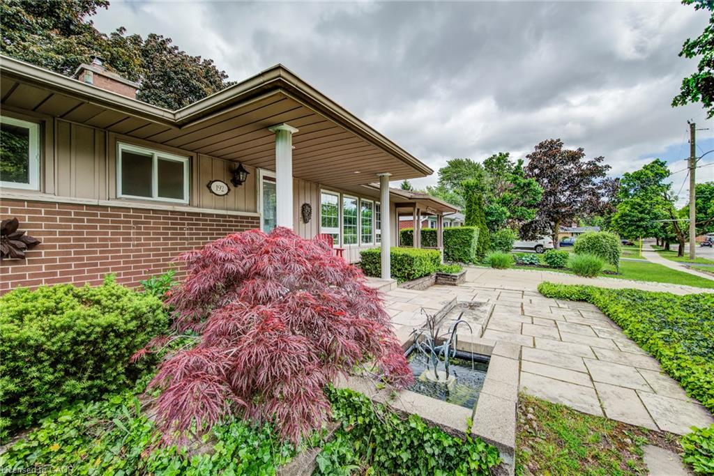 Brick and siding exterior with a covered entry, established landscaping, and a paver stone walkway
