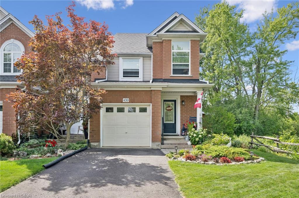 Charming brick Colonial featuring a two-car attached garage, manicured front lawn with mature landscaping, and a welcoming entry with black-trimmed door and sidelights