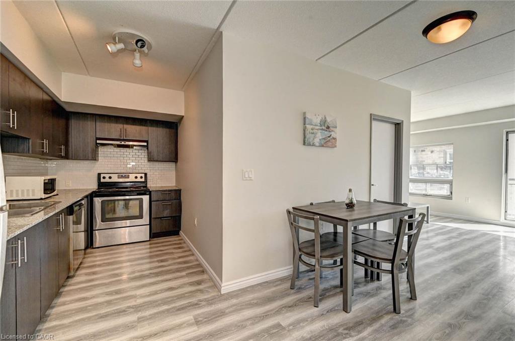 Modern kitchen featuring dark wood-finish cabinetry, stainless steel appliances, a white subway tile backsplash, and light wood-finish flooring