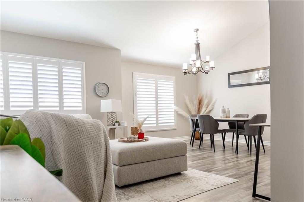 Vaulted ceiling with an overhead chandelier, wood-finish flooring, and white window shutters