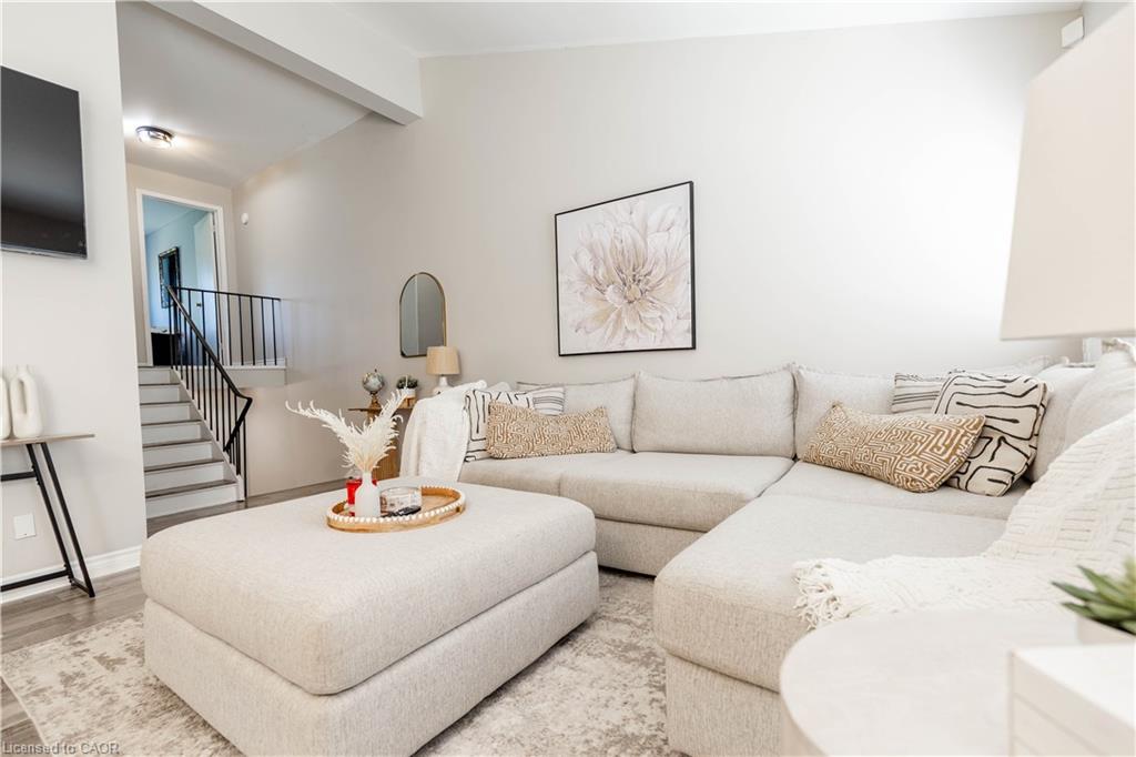 Neutral wall finishes, light wood-finish flooring, and a staircase with black metal railing