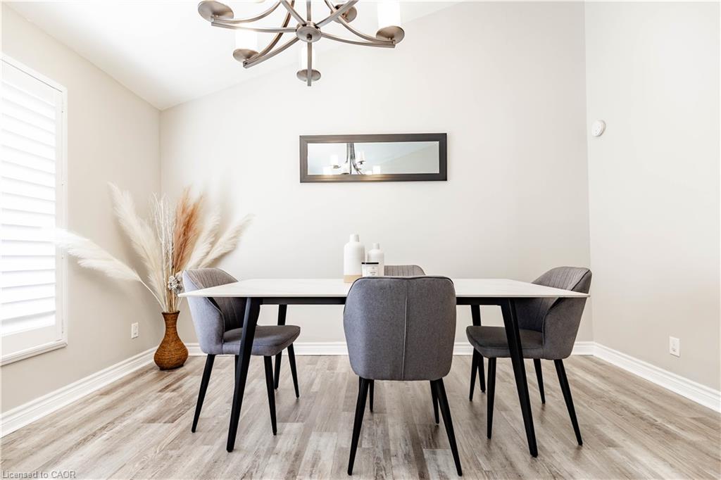 Vaulted ceiling with an updated chandelier, wood-finish flooring, and window shutters
