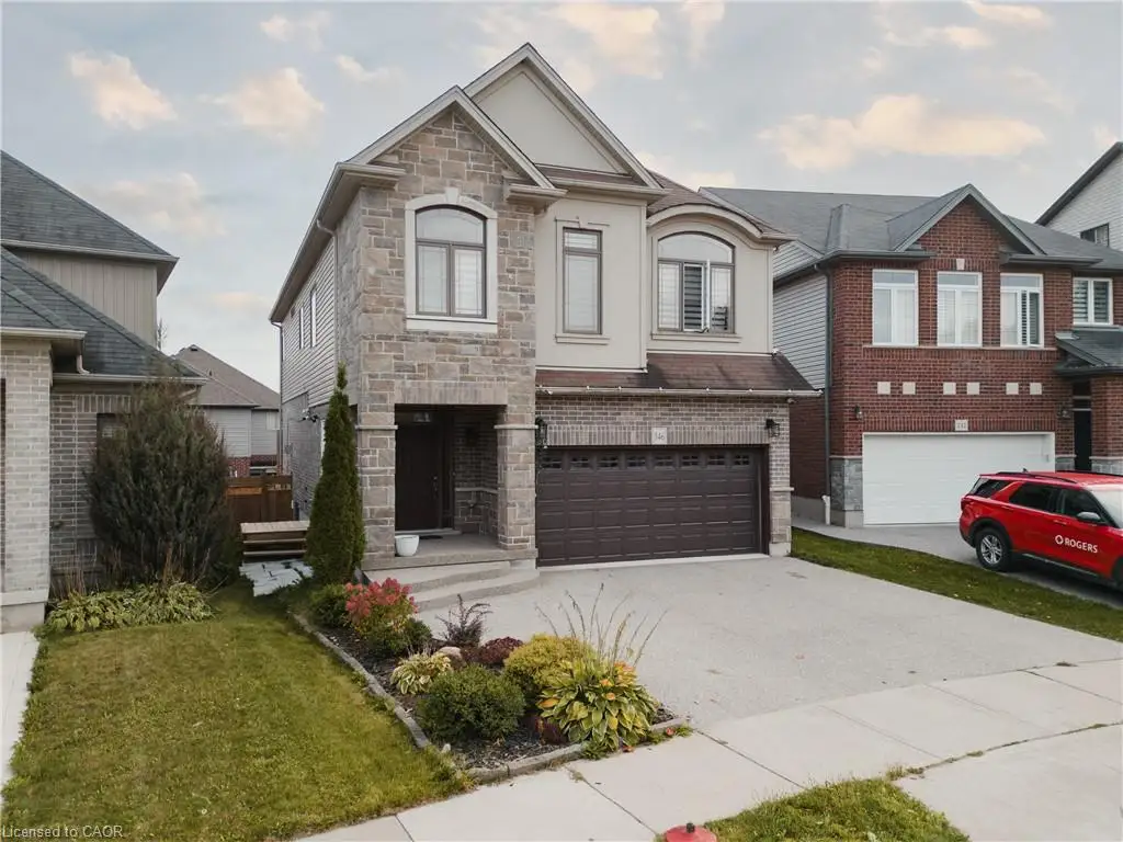 View of front of property with stone siding, driveway, a front yard, stucco siding, and a garage