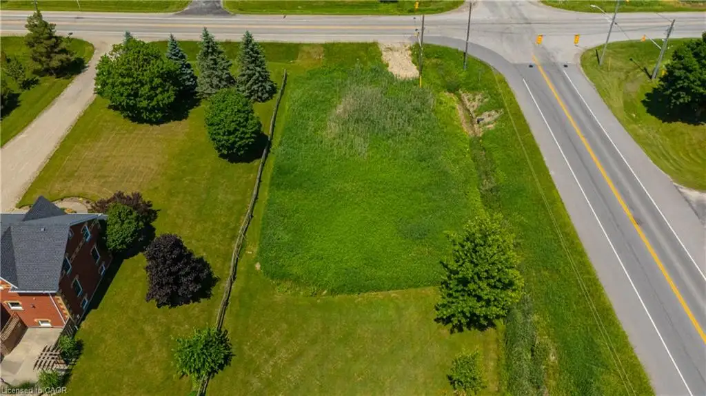 Expansive grassed lot featuring mature trees and a partial wooden fence