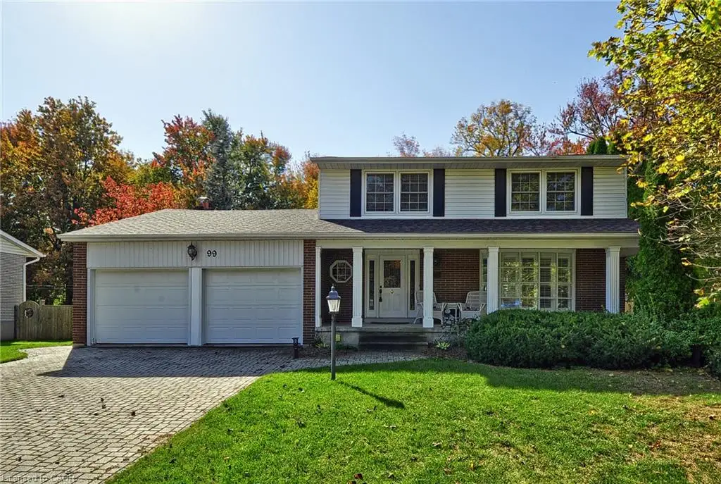 Two-story exterior featuring a brick and siding facade, a covered front entryway with columns, a multi-pane bay window, and a paver stone driveway leading to a two-car garage