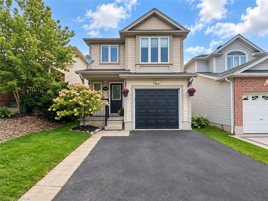 Two-story residence featuring light-colored siding, a dark garage door, and a paved driveway
