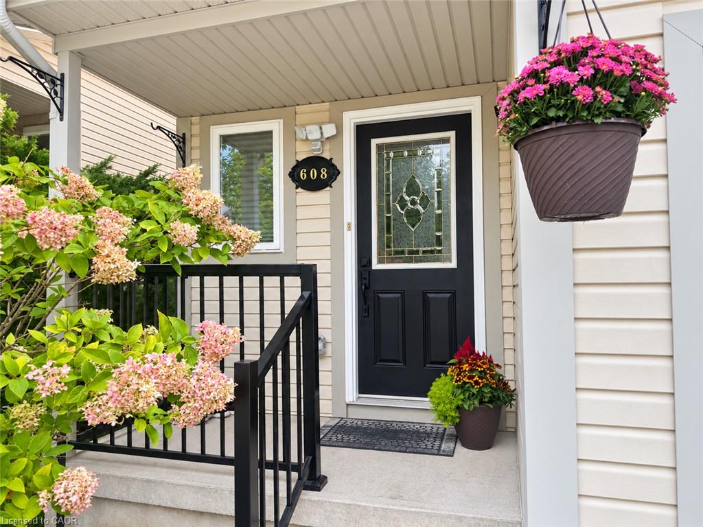 Black entry door with decorative glass insert, concrete front steps, black railing, and beige siding