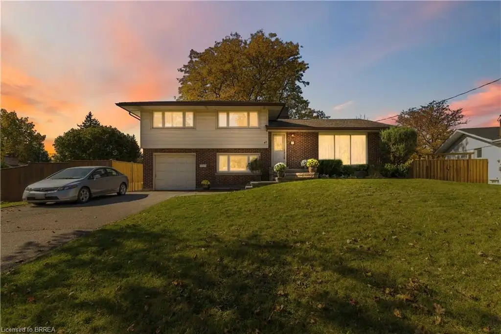 Split-level exterior featuring a multi-material facade of brick and horizontal siding, an attached garage, and a manicured front lawn