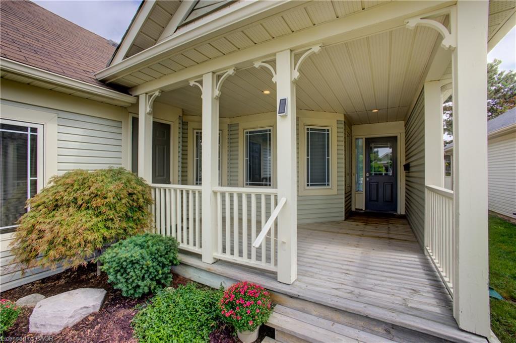 Covered front porch with decorative corbels, wood flooring, and white spindle railings