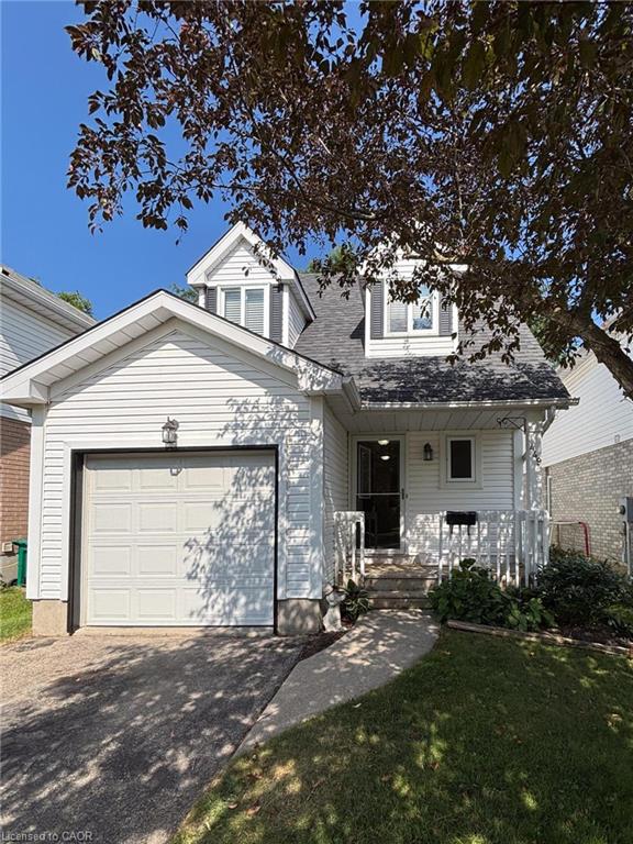 White siding exterior featuring a single-car garage, dormer windows, and a concrete pathway leading to the front entry