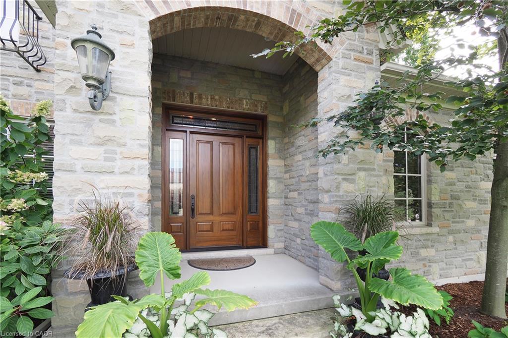 Stone facade featuring a wood-panel entry door with sidelights, an arched portico, and a decorative exterior light fixture