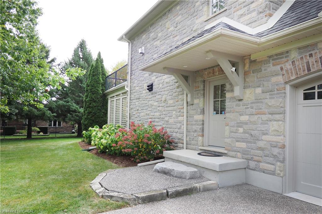 Stone veneer exterior with a covered entry, concrete steps, and a gravel driveway