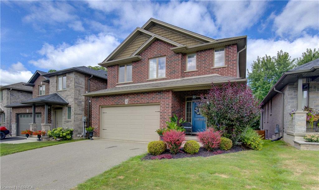 Brick and stone facade, attached two-car garage, paved driveway, landscaped front yard, and a covered front porch